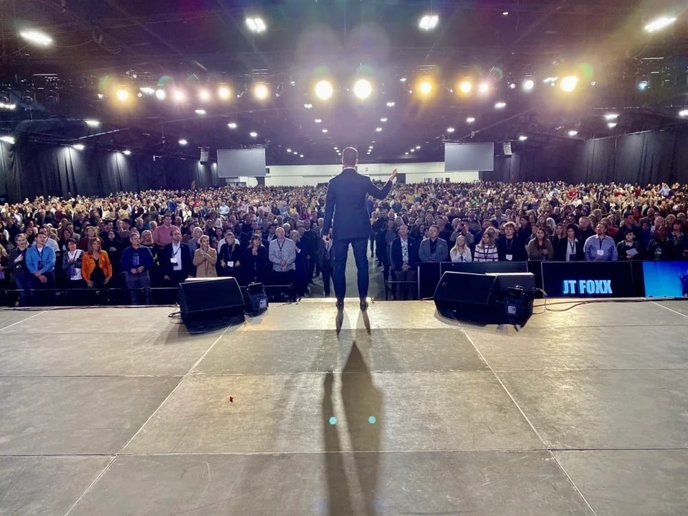 A speaker facing a large standing audience